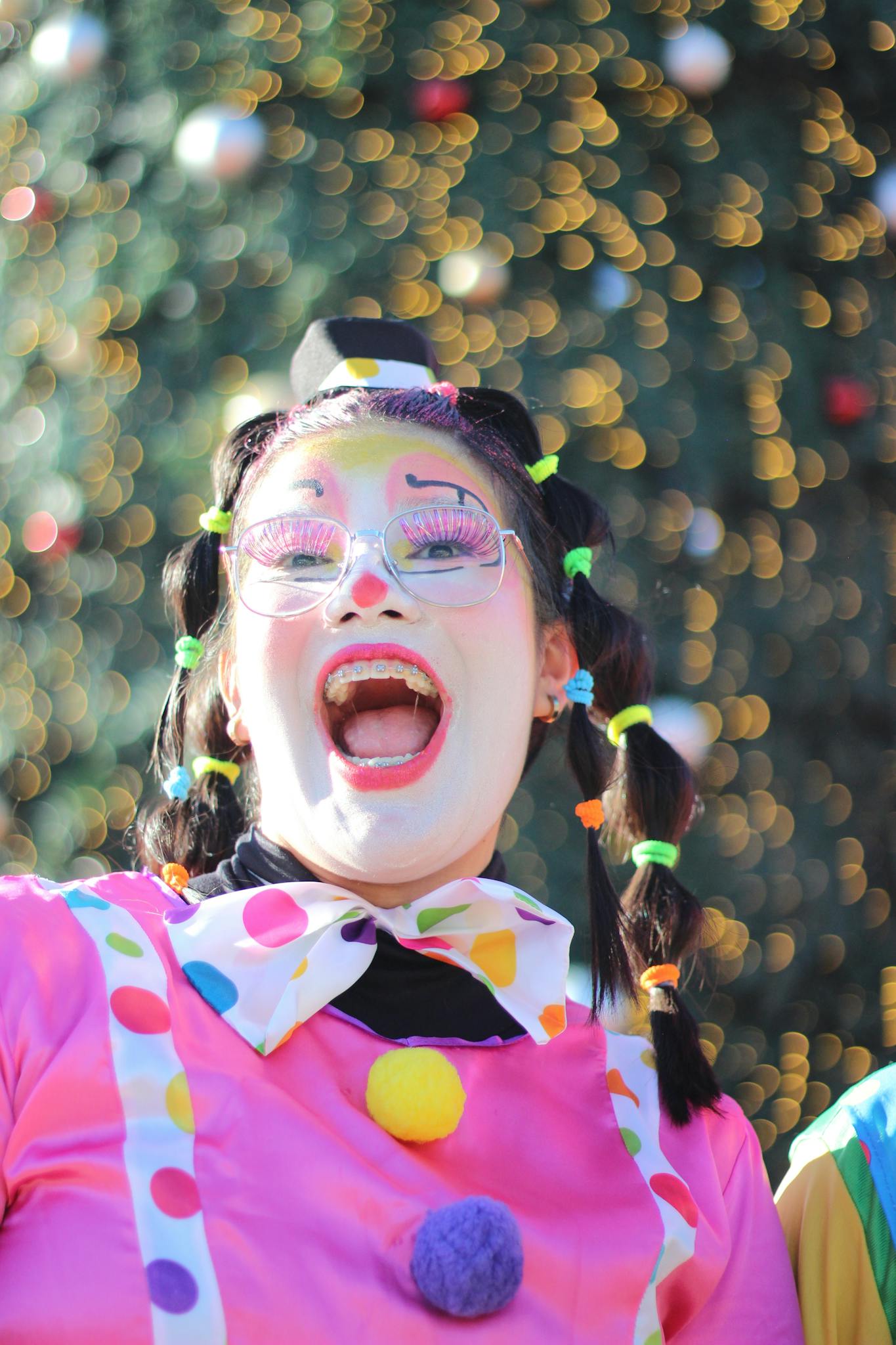 Cheerful clown in colorful makeup and attire performing outdoors, radiating joy.